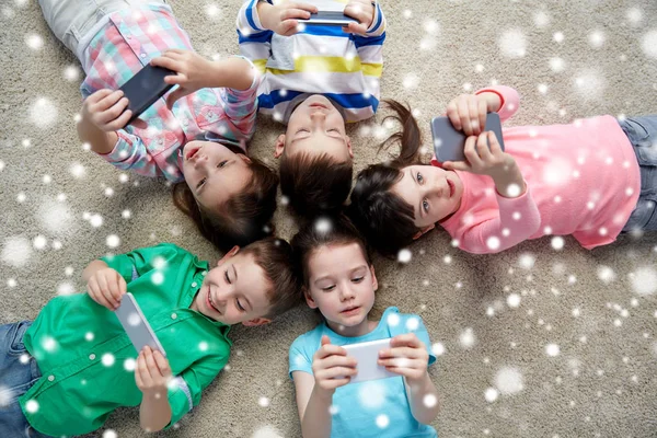 Ευτυχισμένα παιδιά με smartphones που βρίσκεται στον όροφο Royalty Free Εικόνες Αρχείου