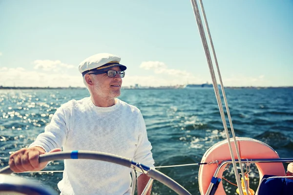 Hombre mayor al timón en barco o yate de vela en el mar — Foto de Stock