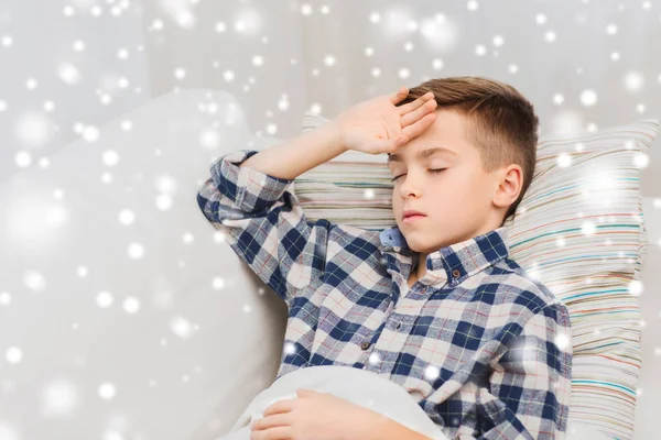 Sjuk pojke i sängen och lider av huvudvärk — Stockfoto