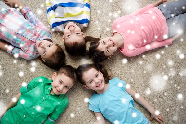 Bambini felici sorridenti sdraiati sul pavimento sopra la neve — Foto Stock