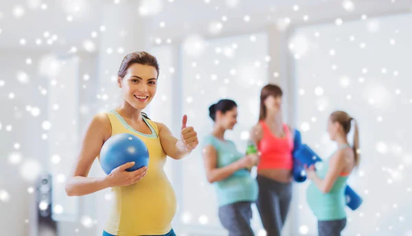 Mujer embarazada con pelota en el gimnasio mostrando los pulgares hacia arriba —  Fotos de Stock