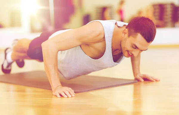 Hombre sonriente haciendo flexiones en el gimnasio — Foto de Stock