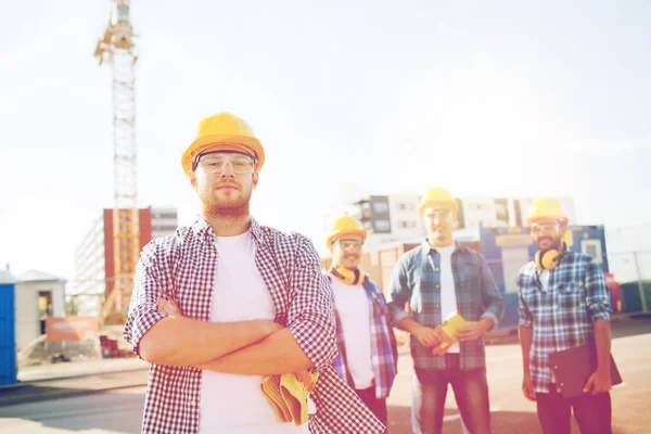 Grupa budowniczych uśmiechający się w hardhats na zewnątrz — Zdjęcie stockowe