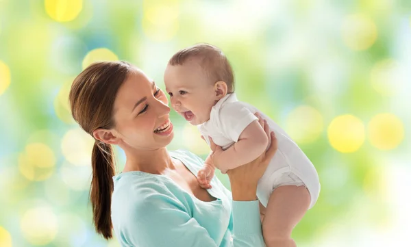 Madre feliz con bebé sobre luces verdes —  Fotos de Stock