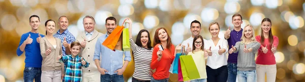 Boldog emberek bevásárló táskák mutatják hüvelykujját fel — Stock Fotó
