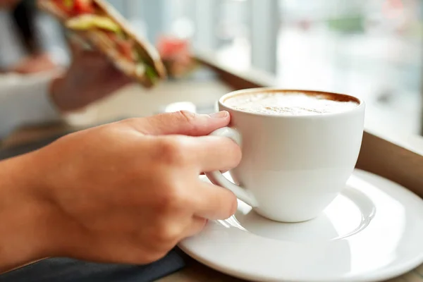 Woman drinking coffee and eating sandwich at cafe — Stock Photo, Image