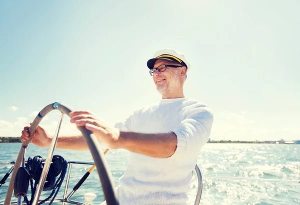 Homem sênior no leme em barco ou iate navegando no mar — Fotografia de Stock