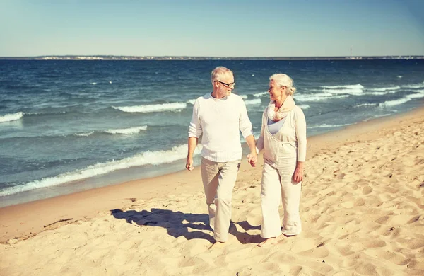 Lyckliga äldre par promenader längs sommar strand — Stockfoto