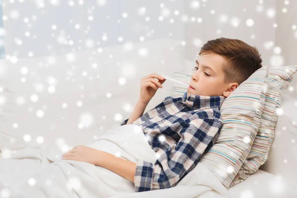 Хворий хлопчик з грипом і термометром вдома — стокове фото