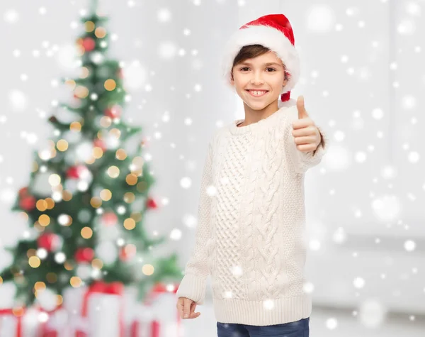 Усміхнений щасливий хлопчик в капелюсі Санта показує великі пальці вгору — стокове фото