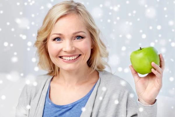 Happy middle aged woman with green apple at home — Stock Photo, Image