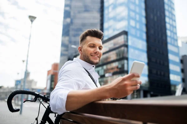 Hombre feliz con smartphone y bicicleta en la ciudad —  Fotos de Stock