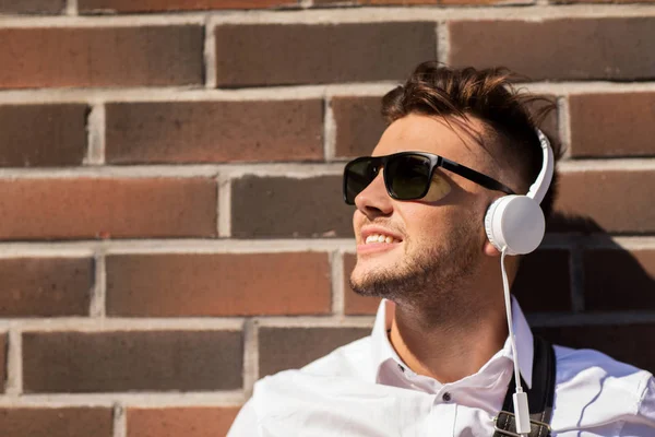 Joven en auriculares sobre muro de ladrillo —  Fotos de Stock