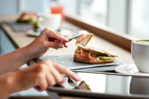 Mujer con tableta pc y panini sándwich en la cafetería —  Fotos de Stock