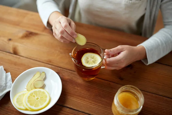 Close up of woman adding ginger to tea with lemon — Stock Photo, Image