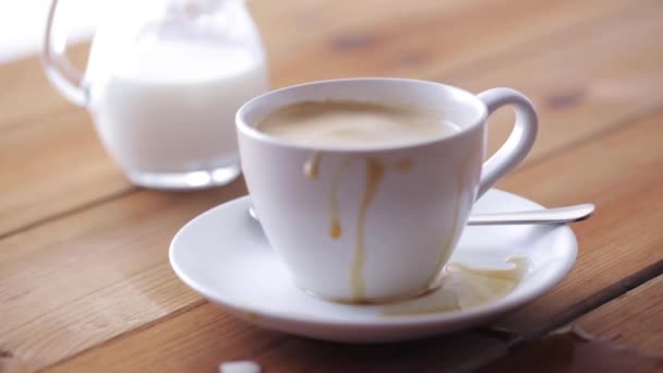 Suiker die vallen bij koffiekopje betreffende houten tafel — Stockvideo