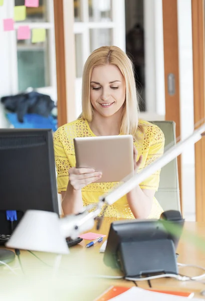 Счастливая творческая женщина с планшетным компьютером в офисе — стоковое фото