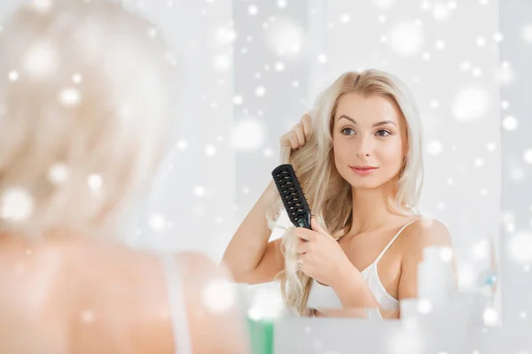 Mujer feliz cepillando el cabello con peine en el baño —  Fotos de Stock