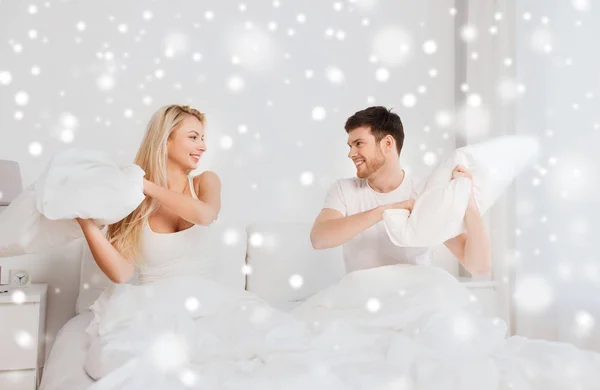 Happy couple having pillow fight in bed at home — Stock Photo, Image