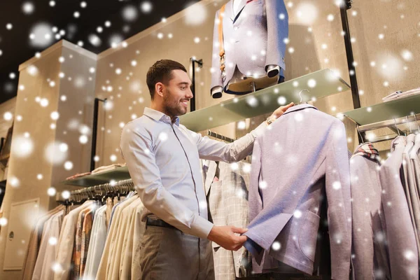 Glad ung man väljer kläder i klädaffär — Stockfoto