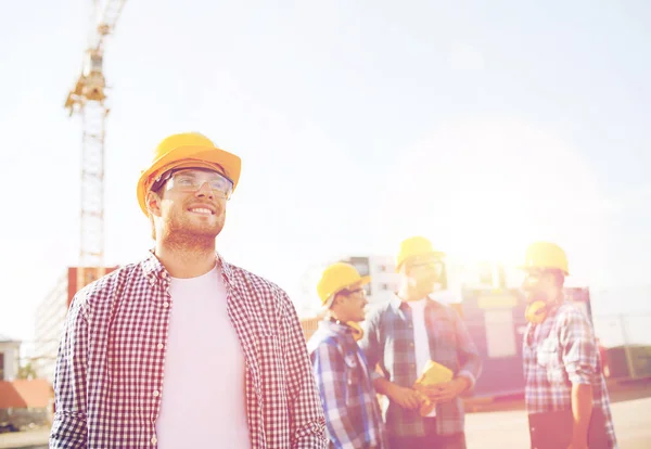 Grupa budowniczych uśmiechający się w hardhats na zewnątrz — Zdjęcie stockowe