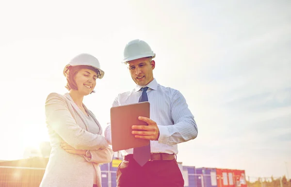 Constructores felices en sombreros con tableta pc al aire libre —  Fotos de Stock