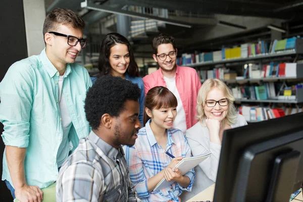 Mezinárodní studenti s počítači v knihovně — Stock fotografie