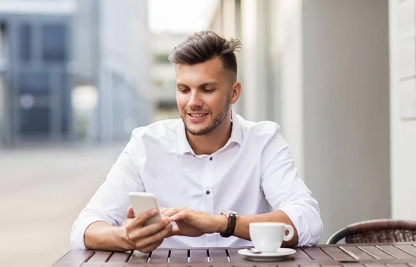Чоловік зі смартфоном і кавою в міському кафе — стокове фото