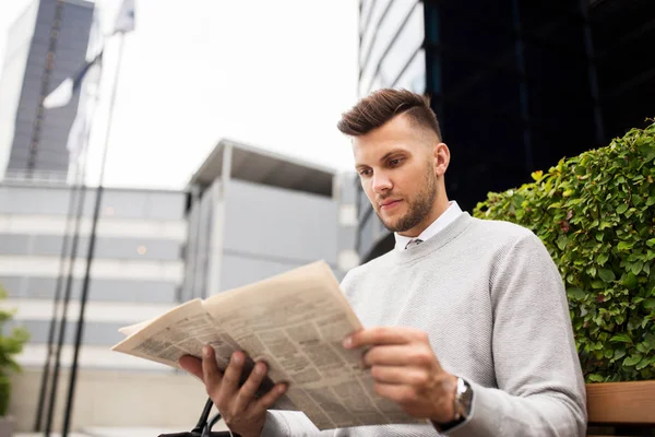 Homem lendo jornal no banco de rua da cidade — Fotografia de Stock