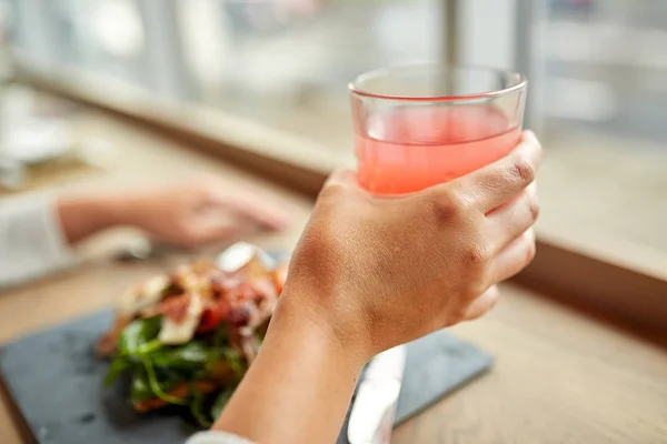 Mano con vaso de jugo y ensalada en el restaurante — Foto de Stock