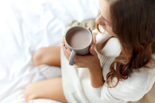 close up of woman with cocoa cup in bed at home