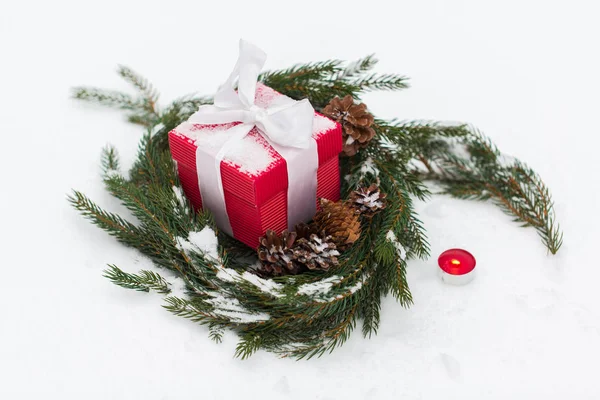 Cadeau de Noël et couronne de sapin avec des cônes sur la neige — Photo