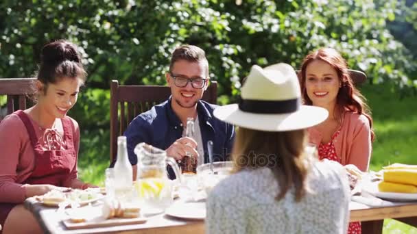 Счастливые друзья, ужинающие на вечеринке в летнем саду — стоковое видео