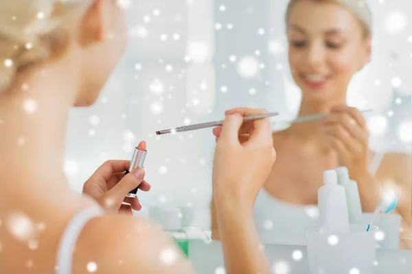 Vrouw met lippenstift en make-up borstel op de badkamer — Stockfoto