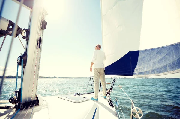 Homem sênior em barco à vela ou iate navegando no mar Fotos De Bancos De Imagens