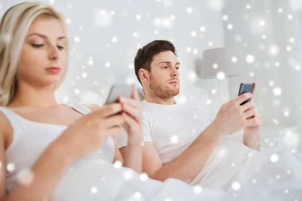 Pareja con smartphones en la cama —  Fotos de Stock