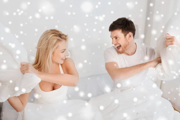 Gelukkige paar met kussen vechten in bed thuis — Stockfoto