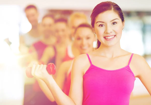 Groupe de personnes souriantes avec haltères dans la salle de gym — Photo