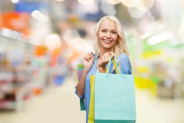 Happy woman with shopping bags at supermarket — Stock Photo, Image