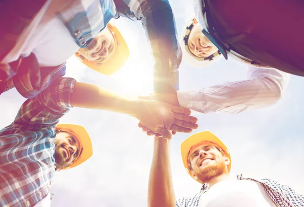 Close up van bouwers in hardhats met handen bovenop — Stockfoto