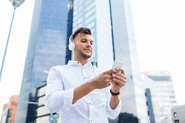 Homem com fones de ouvido e smartphone ouvindo música — Fotografia de Stock