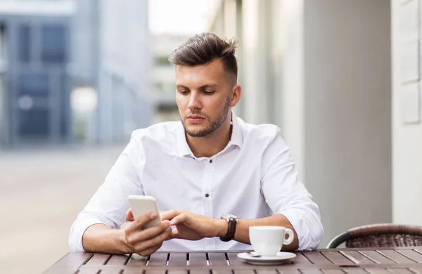 Чоловік зі смартфоном і кавою в міському кафе — стокове фото