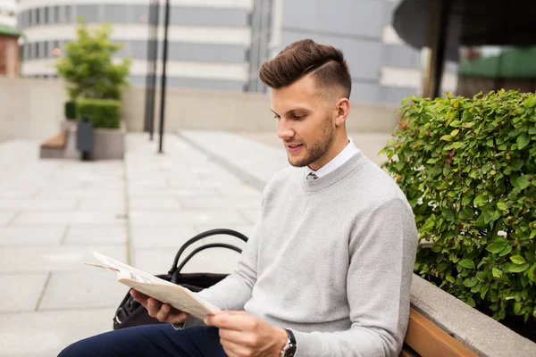 Usmívající se muž čtenářský deník na městské ulici lavička — Stock fotografie