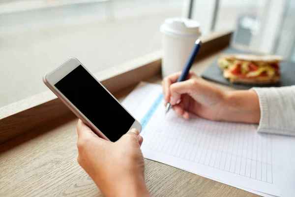 Woman with smartphone and paper form at cafe — Stock Photo, Image