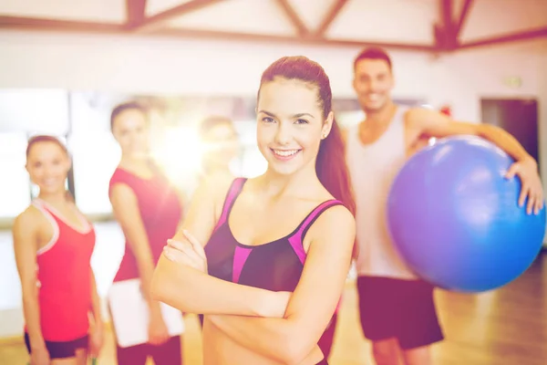 Donna in piedi davanti al gruppo in palestra — Foto Stock