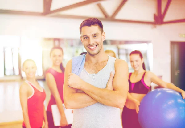 Uomo sorridente in piedi davanti al gruppo in palestra — Foto Stock