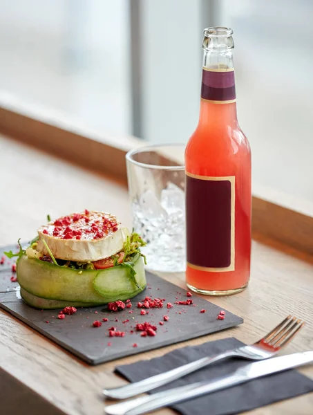 Salada, garrafa de bebida, vidro e talheres na mesa — Fotografia de Stock