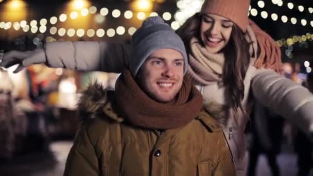 Щаслива пара обіймається на різдвяному ринку — стокове відео