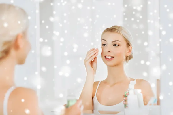 Nuori nainen kosteusemulsio pesu kasvot kylpyhuoneessa — kuvapankkivalokuva