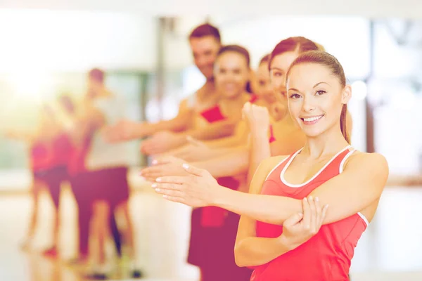 Grupp av leende människor sträcker sig i gymmet — Stockfoto